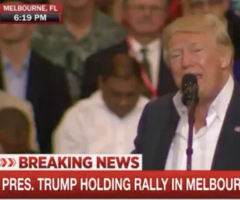 President Trump speaking at a rally in Melbourne, Florida; news ticker below him displaying breaking news.