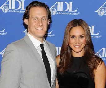 Two people smiling at an Anti-Defamation League event, posing in front of a blue backdrop with the logo.