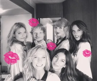A group of smiling people posing for a photo. Pink lipstick marks are added to the image.