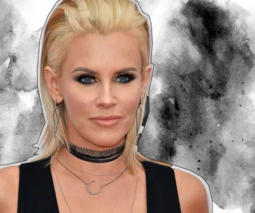 A person with blonde hair, wearing geometric earrings and layered necklaces, against a gray abstract background.