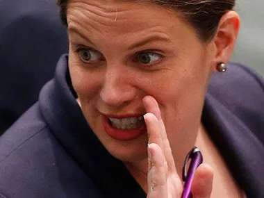 Woman speaking animatedly, holding a purple pen.