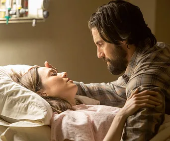 Man comforting woman in hospital bed with caring expression.