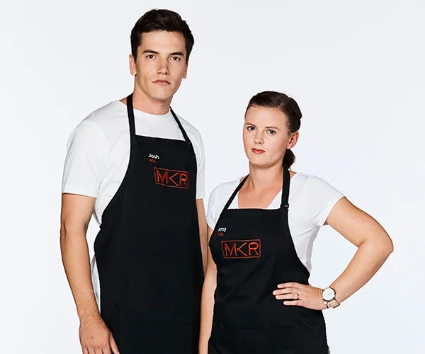 Josh and Amy from My Kitchen Rules, wearing black aprons with the MKR logo, standing against a plain white background.