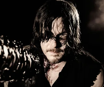 Dark, intense scene featuring a long-haired man with a grim expression, holding a weapon wrapped with barbed wire.