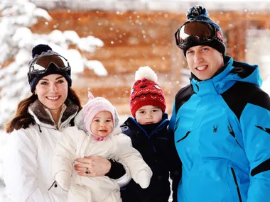 A family wearing winter clothes poses for a photo in a snowy outdoor setting.