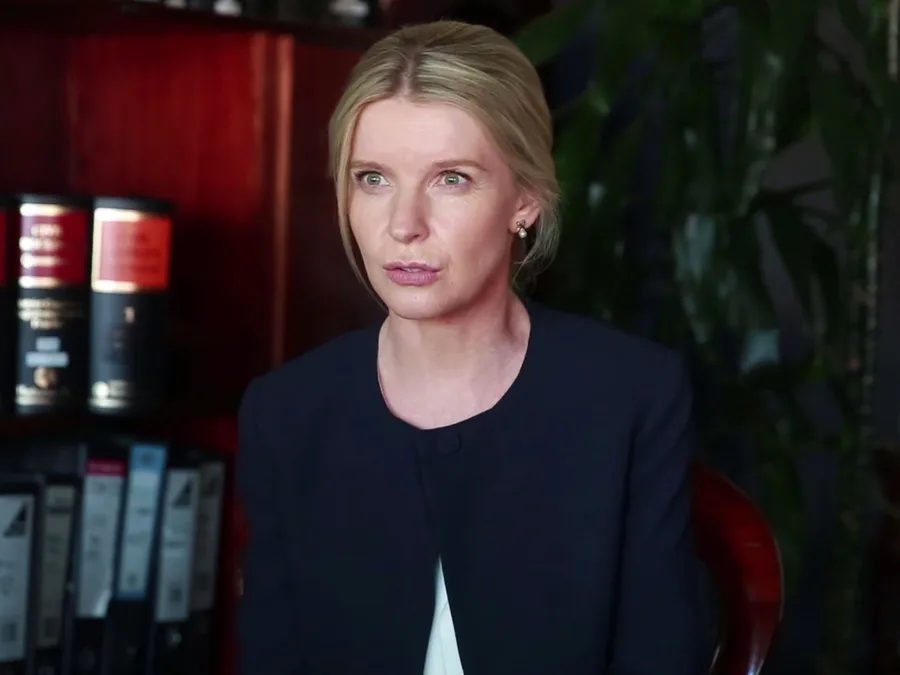A woman in an office setting with books and files in the background, from the movie "Don't Tell" (2017).