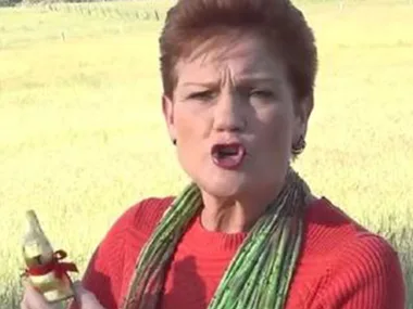 A woman in a red sweater holds a chocolate Easter bunny in a field, speaking passionately.