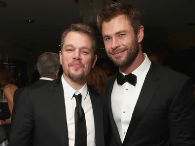 Alt text: "Two well-dressed men smiling at an event."