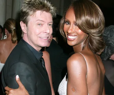 A couple smiling at a formal event, with the woman in a white dress and the man in a black suit.