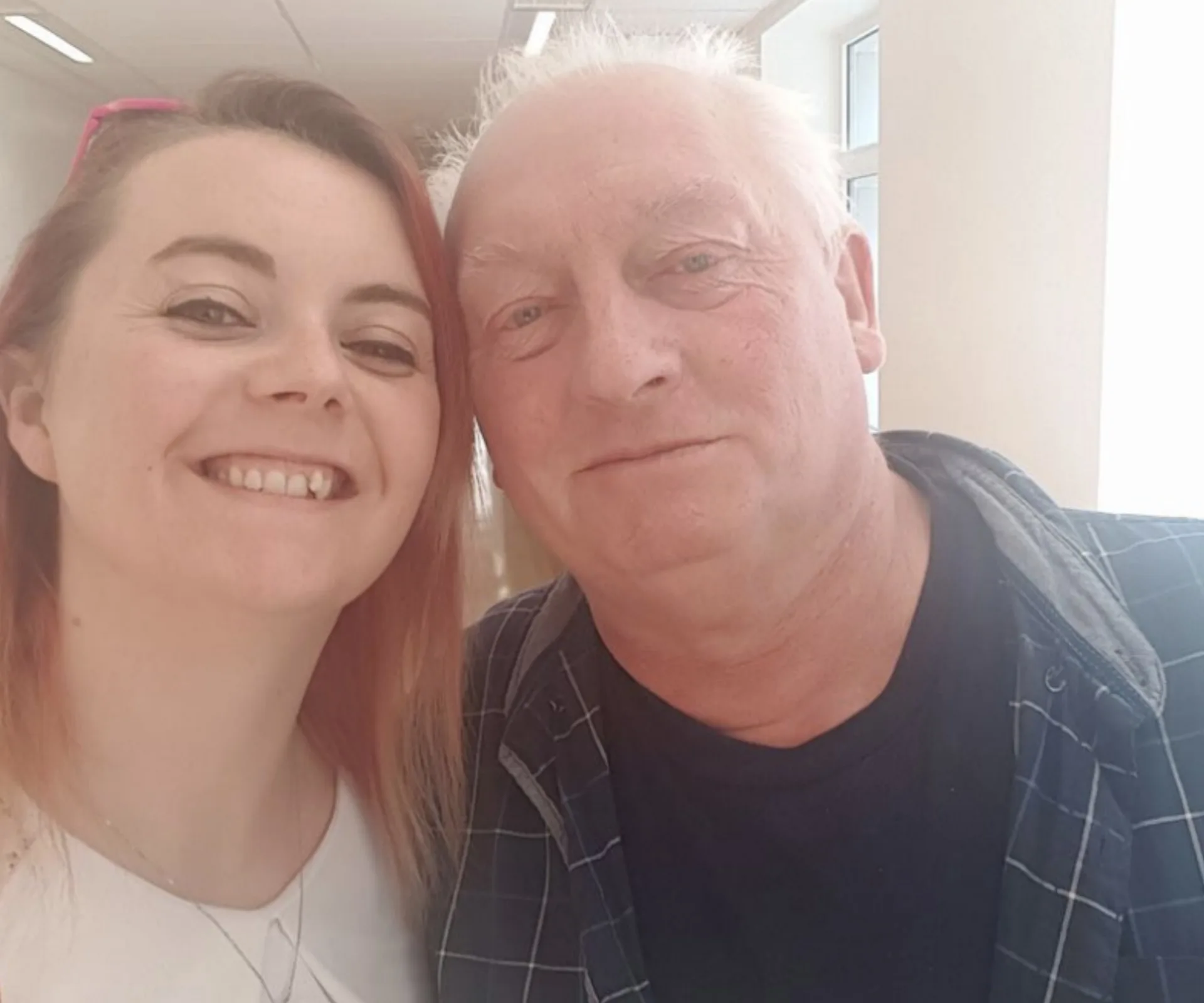 A woman and an older man smiling together in a bright room.