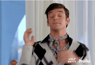 A man in patterned clothes dramatically flicks his hands near his face, with "Ugly Betty" and "hulu" logos visible.