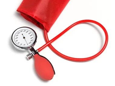 Blood pressure monitor with red cuff and bulb on a white background.