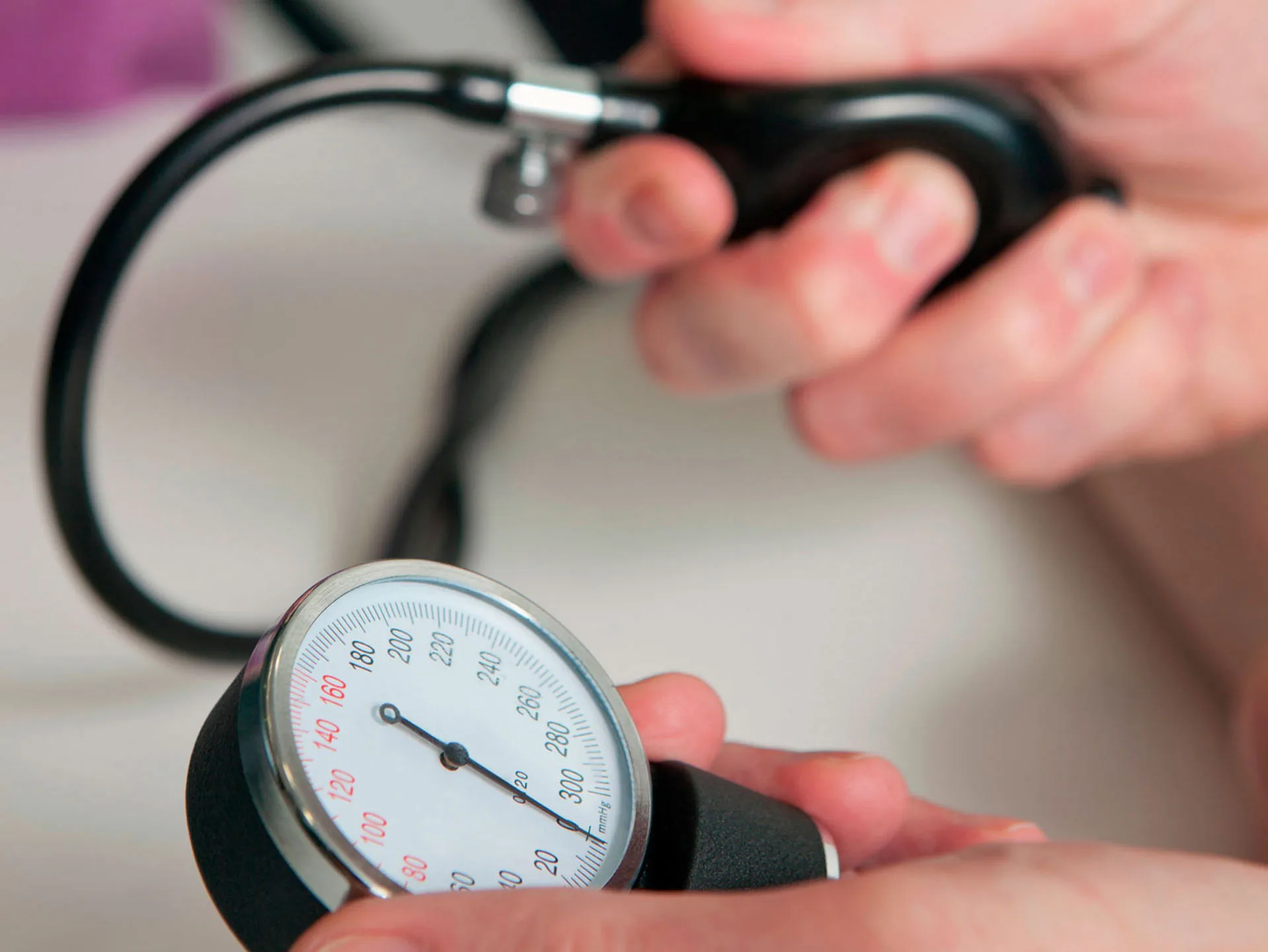 "A hand using a manual blood pressure monitor, focusing on the gauge."