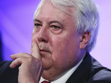 A thoughtful man with white hair in a suit, holding his chin with a contemplative expression against a purple background.