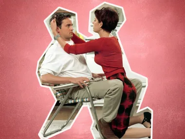A woman in a red top straddles a man sitting in a chair, both looking at each other intently.