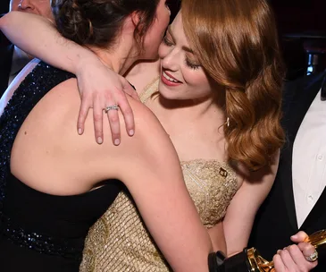 Two people hugging closely, with one holding an award.