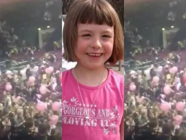 Young girl smiling next to a blurred crowd scene at concert.