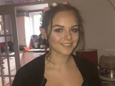 Young woman smiling with floral headband, indoors.