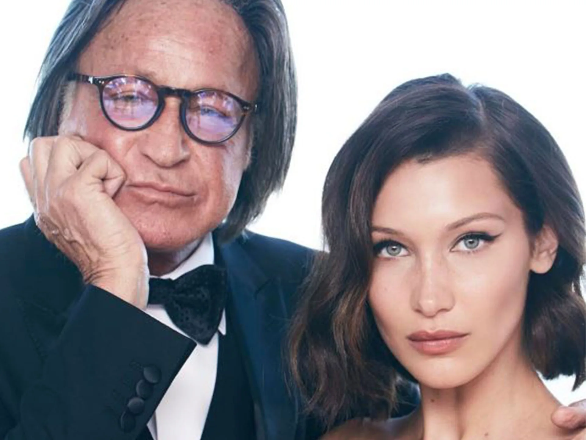 Two individuals posing closely together, one wearing glasses and a bow tie, the other with dark hair and a neutral expression.