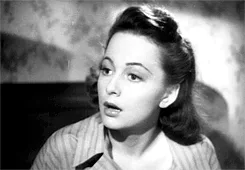 Black and white image of a woman looking surprised, wearing a striped top, with 1940s hairstyle.