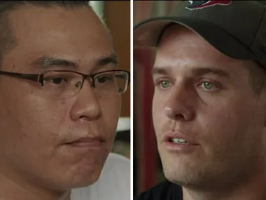 Two men giving an interview in prison setting, one wearing glasses, the other a cap.
