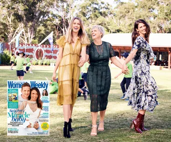 Three women holding hands and smiling in a grassy area, with children playing in the background. Magazine cover inset.