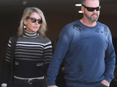A man and woman in sunglasses walking together, dressed in casual attire.