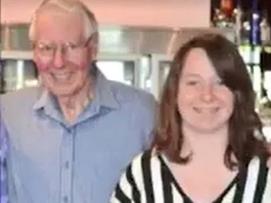 An older man and a young woman smiling, standing together.