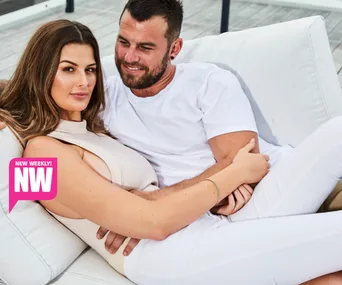A couple sitting together on a white couch outdoors, smiling and relaxed.