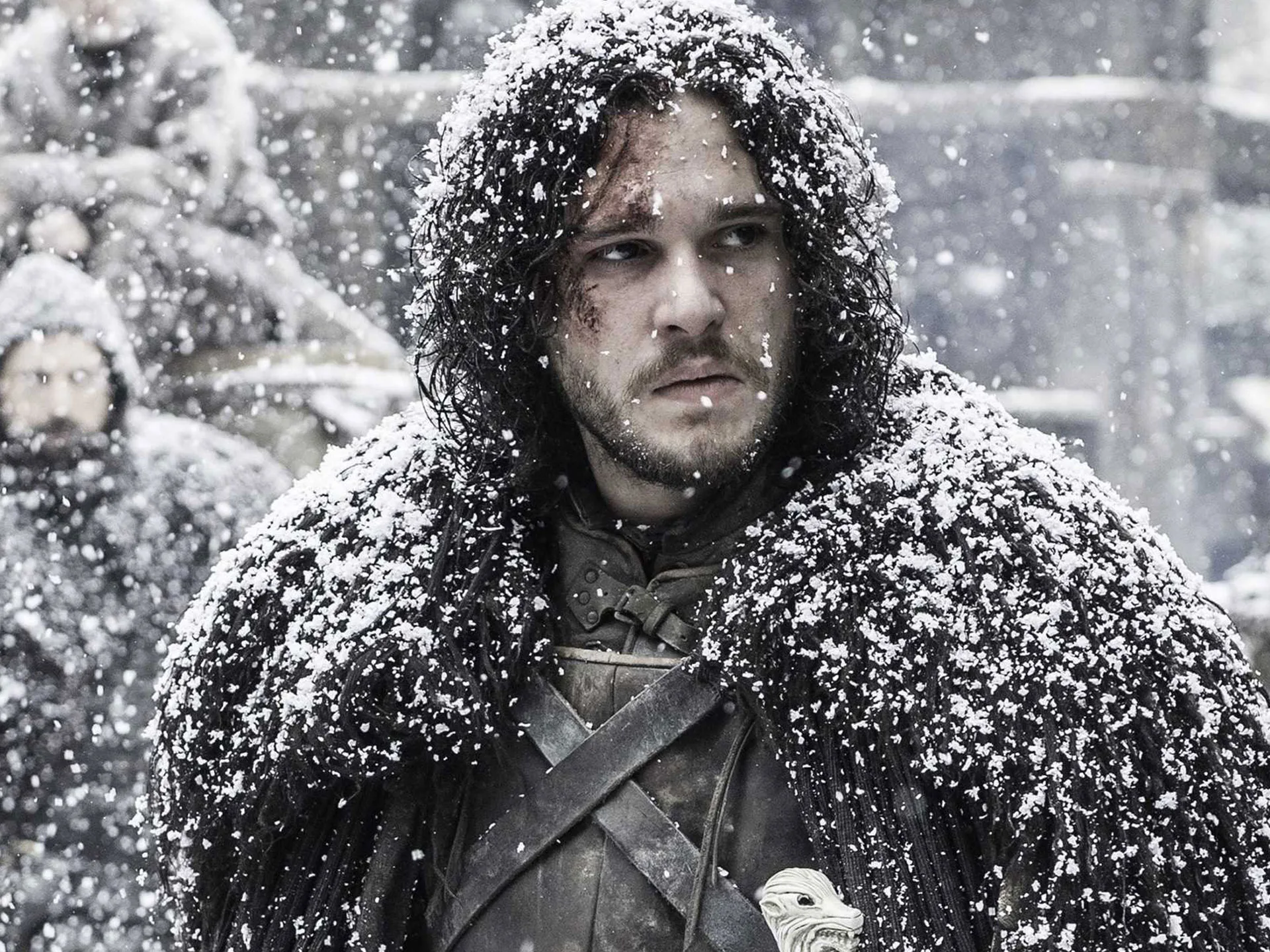 Character standing in falling snow, wearing a fur cloak, looking serious.