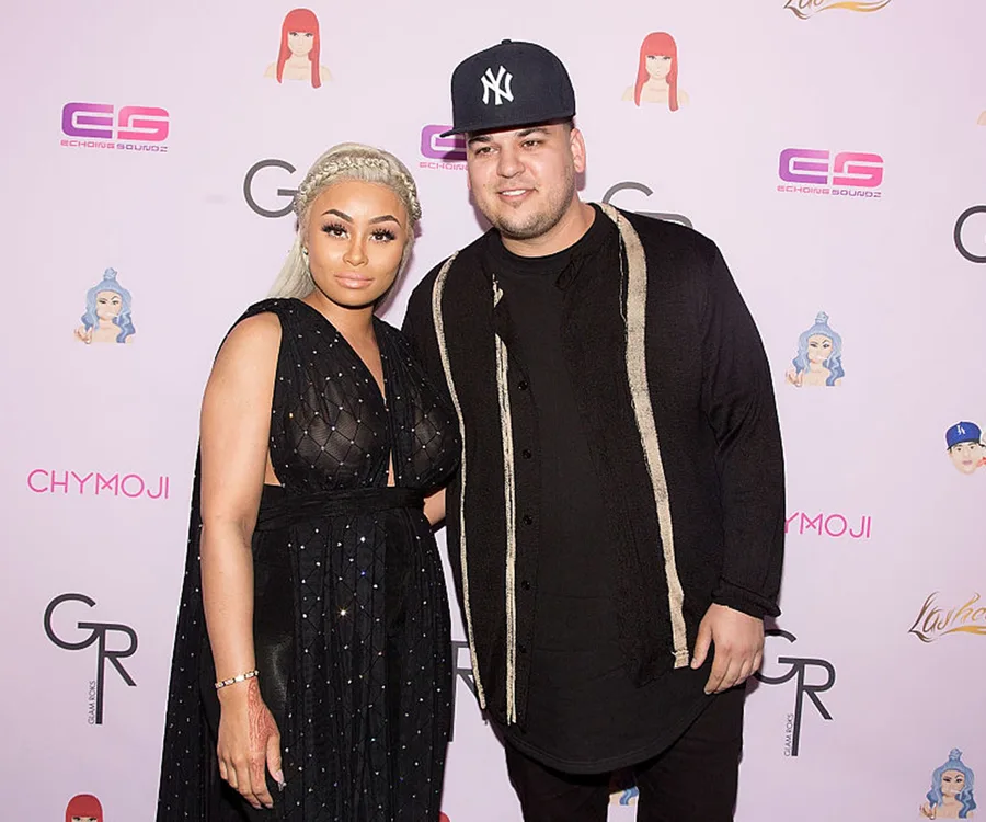 Celebrity couple posing at a Chymoji event with branded background.
