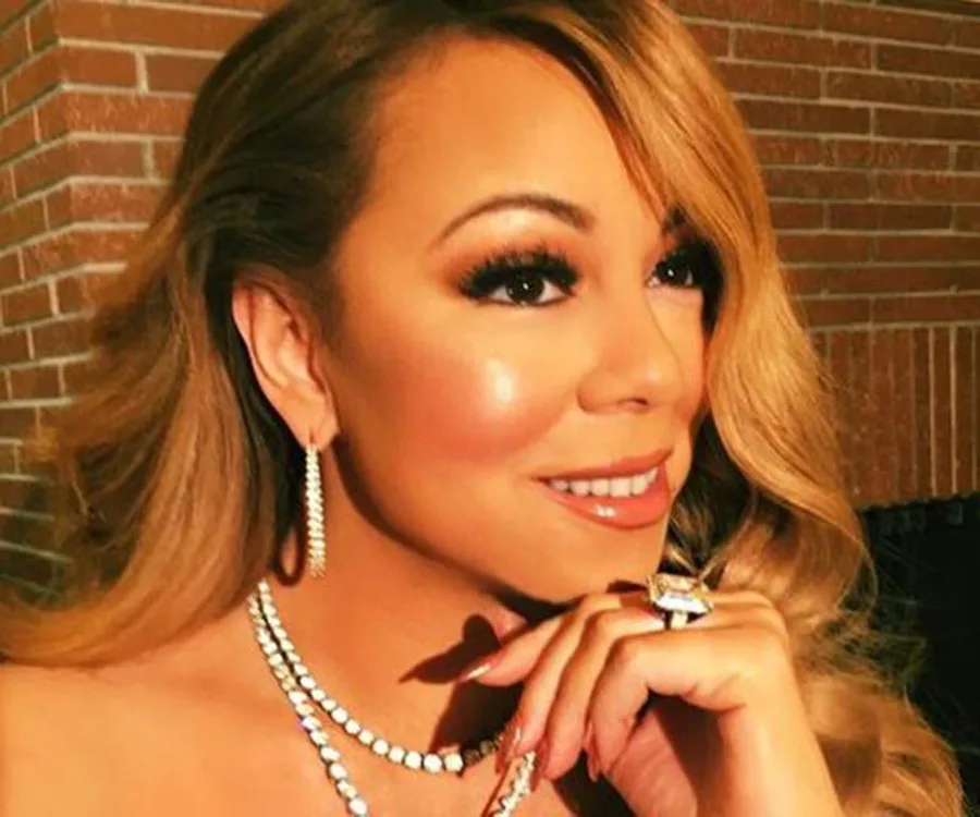Close-up of a woman with long hair, wearing diamond jewelry, smiling slightly to the side.