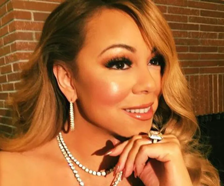 Close-up of a woman with long hair, wearing diamond jewelry, smiling slightly to the side.