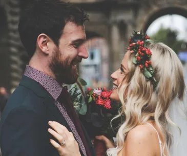 Bride and groom smiling at each other, bride wearing flower crown.