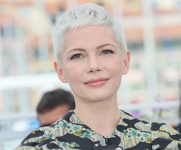 Short-haired woman in a floral-patterned outfit gazing slightly away from the camera with a calm expression.