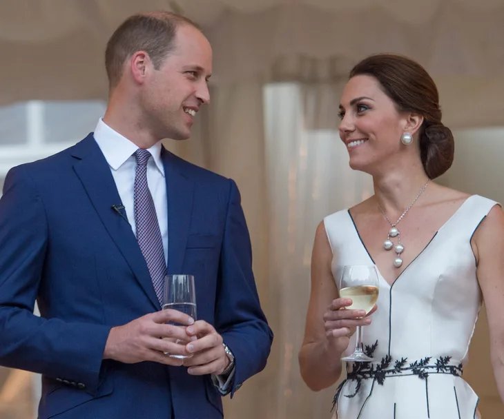 Two people smiling and holding drinks, dressed formally, at an event.