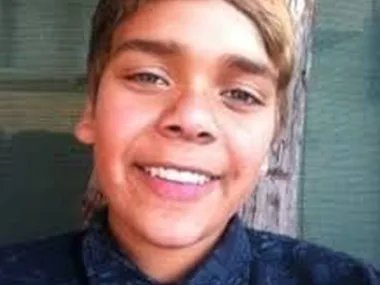 A smiling young person with light hair against a neutral background.