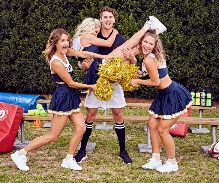 Group photo from Bachelor Australia 2017: four people in cheerleading outfits, playful pose with pom-poms.
