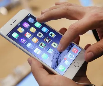 Hands using an iPhone, navigating apps on the home screen, demonstrating a keyboard swipe feature.