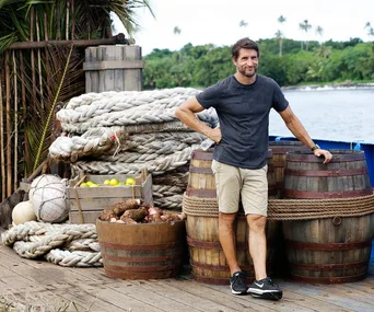 Man stands by barrels and ropes on a dock, tropical scenery in background, possibly related to "Australian Survivor 2017."