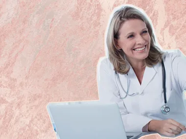 Smiling female doctor with a stethoscope, sitting in front of a laptop against a marbled background.