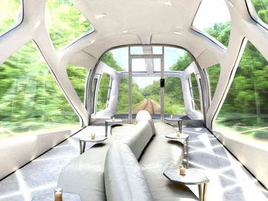 Luxurious Japanese train interior with plush seating, large windows offering scenic views of lush greenery.