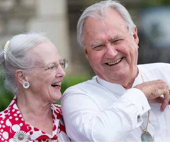 Two elderly people laughing together outdoors.