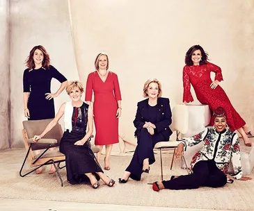 A group of six women in elegant attire posing confidently for a professional photoshoot.