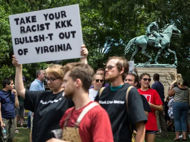 Protesters in Virginia with a sign opposing racism in front of a Confederate statue.