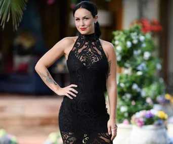 Person in a black lace dress, standing outdoors with colorful flowers in the background.