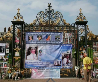 A memorial with flowers and photos of Princess Diana on ornate gates at Kensington Palace.
