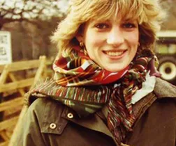 Young woman in a colorful scarf outdoors, smiling warmly.