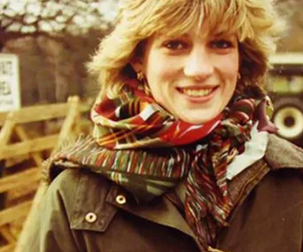 Young woman in a colorful scarf outdoors, smiling warmly.