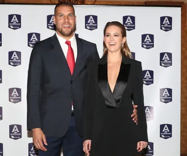 Two people smiling at an event, standing in front of a backdrop with "All Australian" logos.